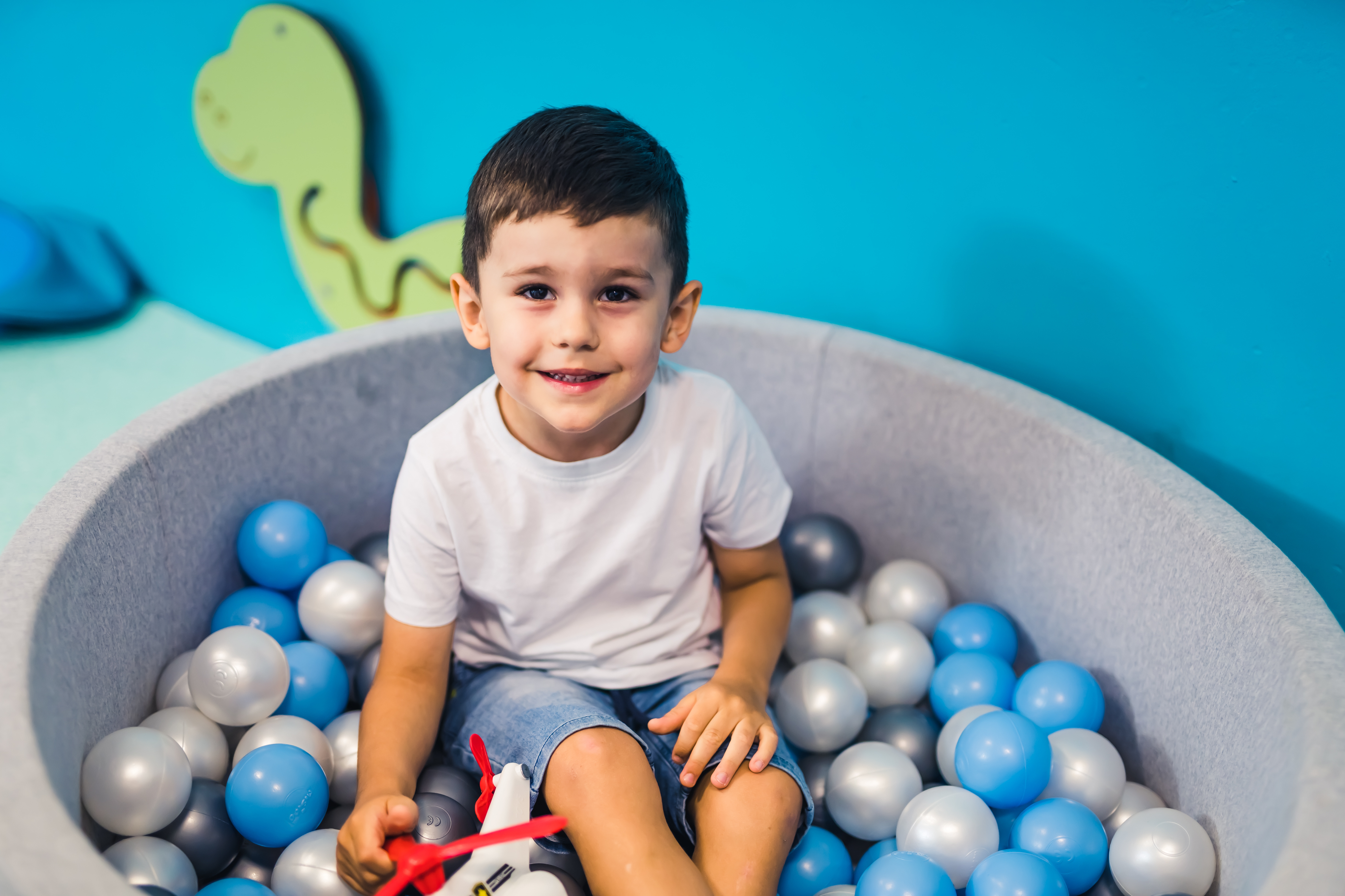 Toddler boy playing with a toy in a ball pit full of colorful balls. Exercise sensory system while being mindful, relaxed and having fun. Sensory play at the nursery school.