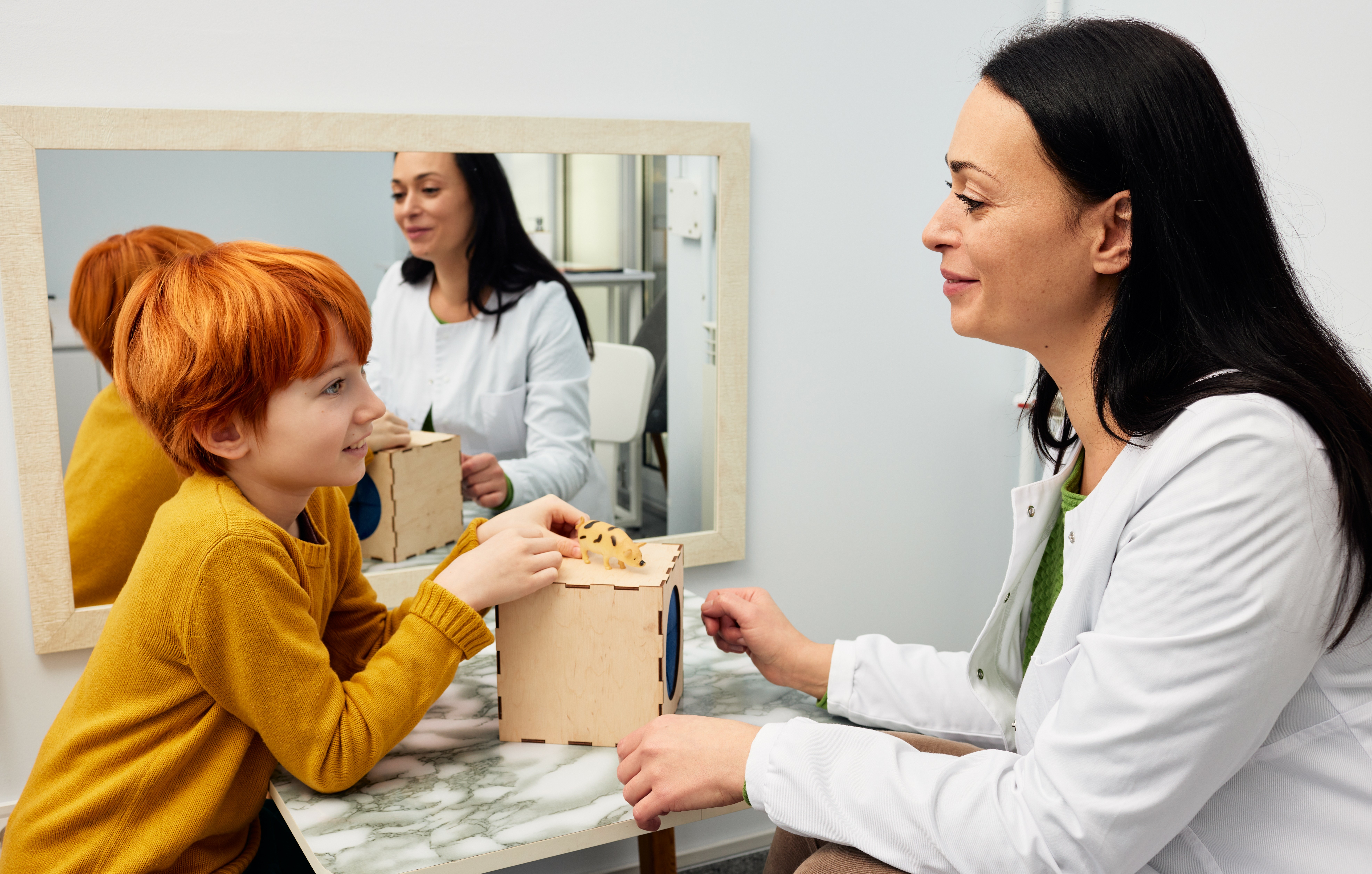 Female psychologist working with boy patient in office while play therapy session. Mental health for kids